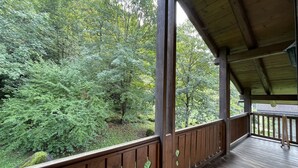 Een houten terras met uitzicht op een dicht bos.