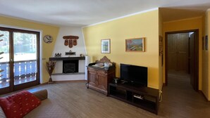 Ein Wohnzimmer mit Kamin, Fernseher und einer Tür zu einem anderen Raum.