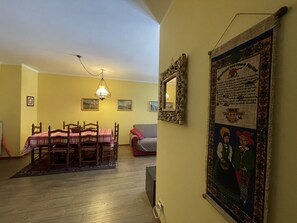 Uma sala de jantar com mesa e cadeiras, um lustre e um espelho fixado na parede.