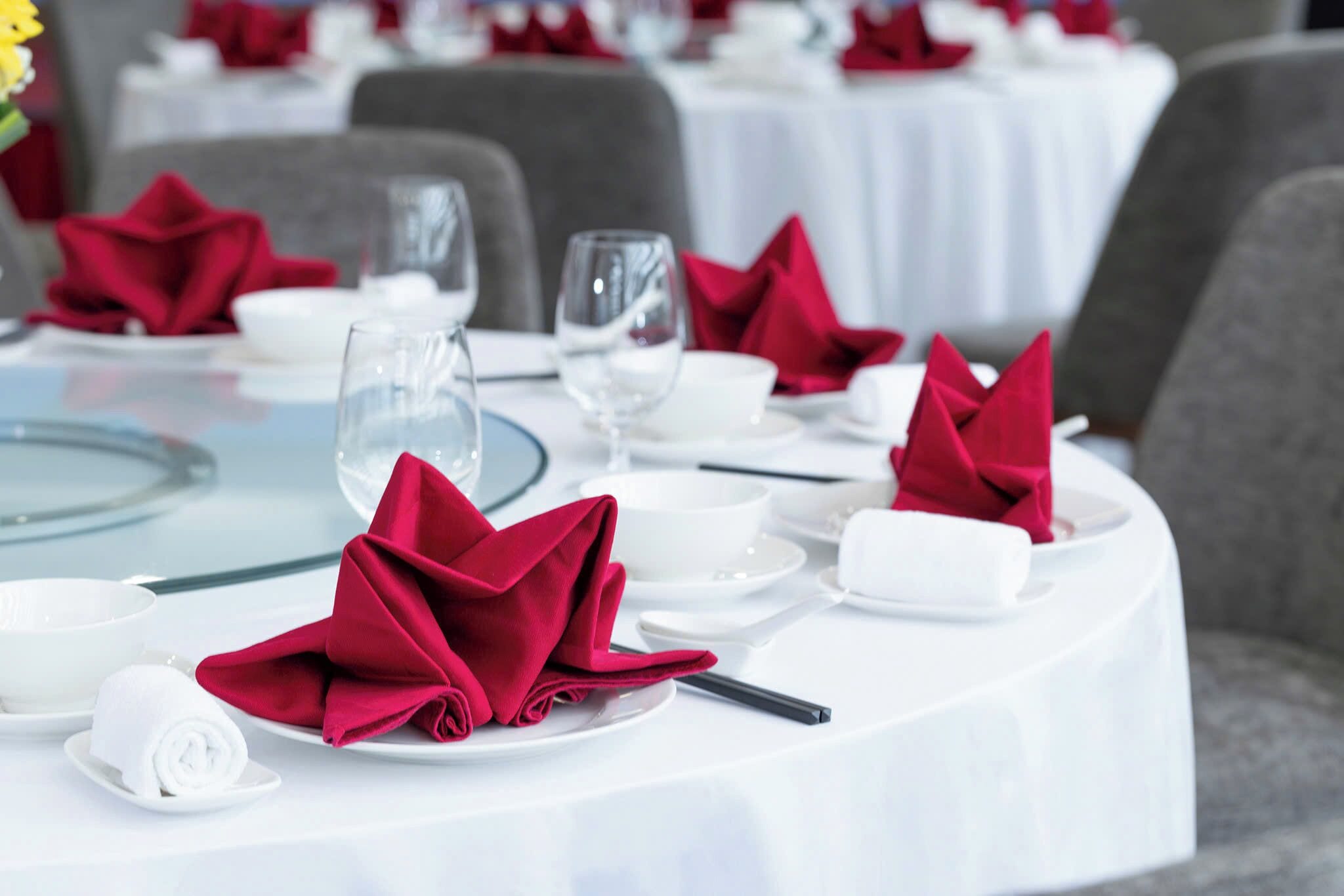 Una mesa dispuesta con platos blancos, servilletas rojas y copas de cristal.