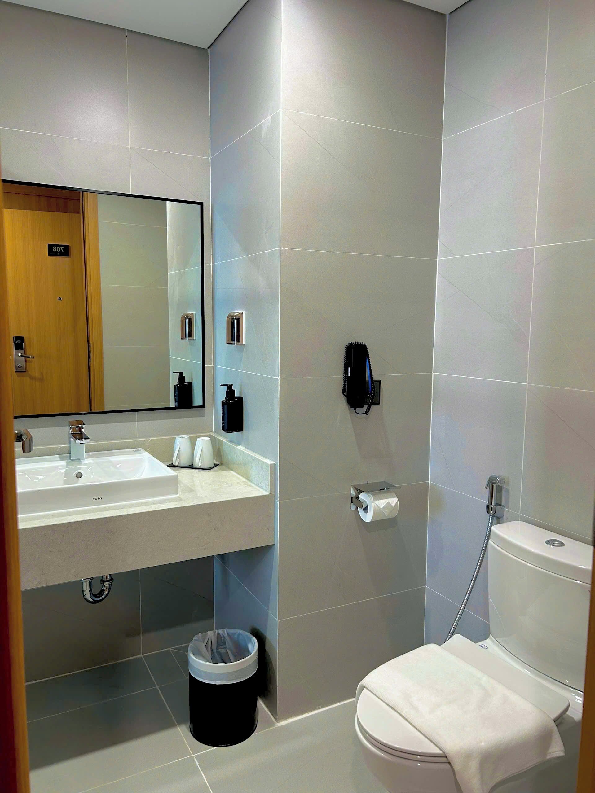 Un baño moderno con lavamanos, espejo, inodoro y ducha.