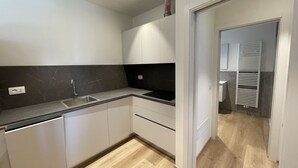 Una cucina moderna con mobili bianchi, un piano di lavoro nero e un pavimento in legno.