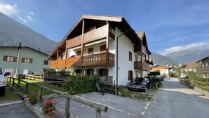 Ein Chalet im traditionellen Stil mit Holzbalkon, gepflasterter Auffahrt und Bergblick.