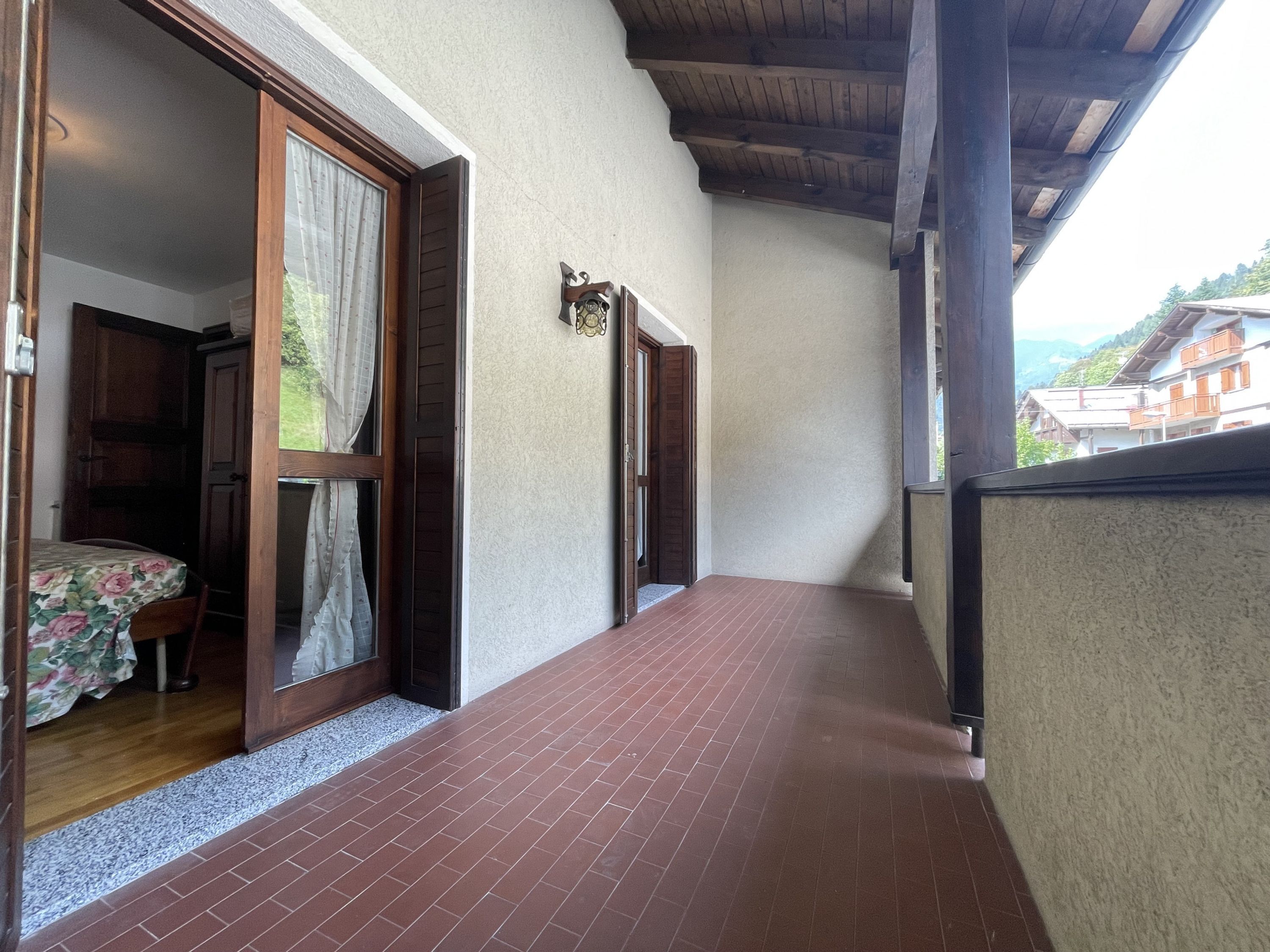Un corridoio con porte in legno che conduce a una stanza con un letto e una sedia.