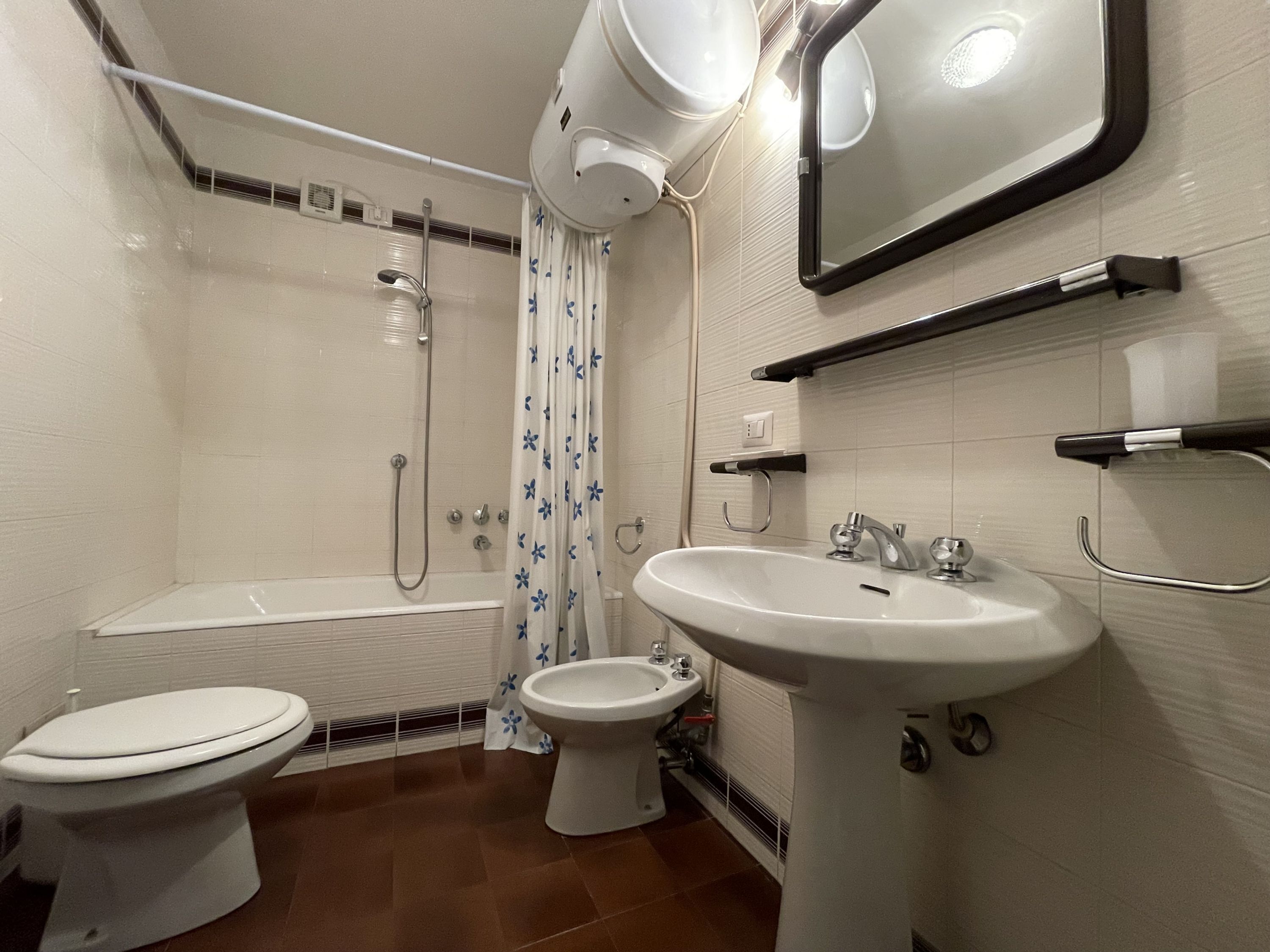 A bathroom with a toilet, bidet, bathtub, and sink.