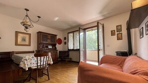 Ein gemütliches Wohnzimmer mit Holzboden, einem Esstisch mit Stühlen, einer Couch und einem Schrank.