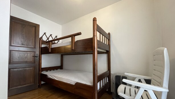 Ein Stockbett in einem Raum mit Holzboden und einer weißen Tür.