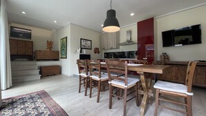 A modern kitchen with wooden furniture, a dining area, and a staircase leading to an upper level. - 067 Bilocale Piano Terra Giustino (Giustino)