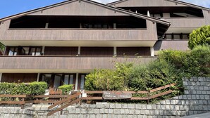 A multi-story building with a stone facade and a wooden deck. - 079 Bilocale Pinzolo (Pinzolo)