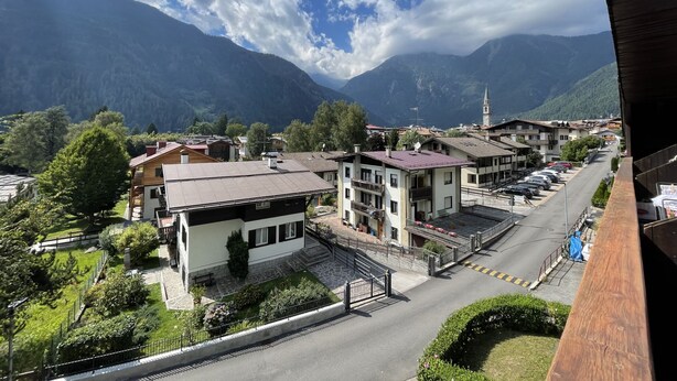 A mountain town with buildings, a street, and a mountain backdrop. - 079 Bilocale Pinzolo (Pinzolo)