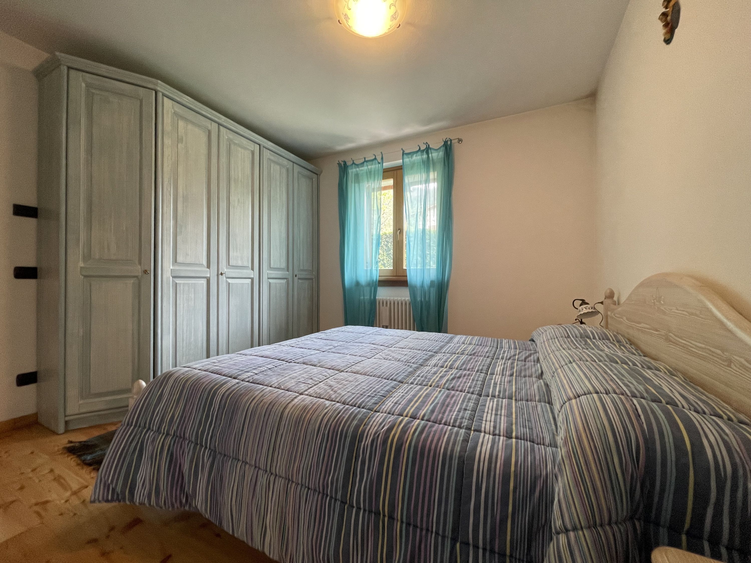 Ein Schlafzimmer mit einem Bett, einem Kleiderschrank und einem Fenster mit Vorhängen.