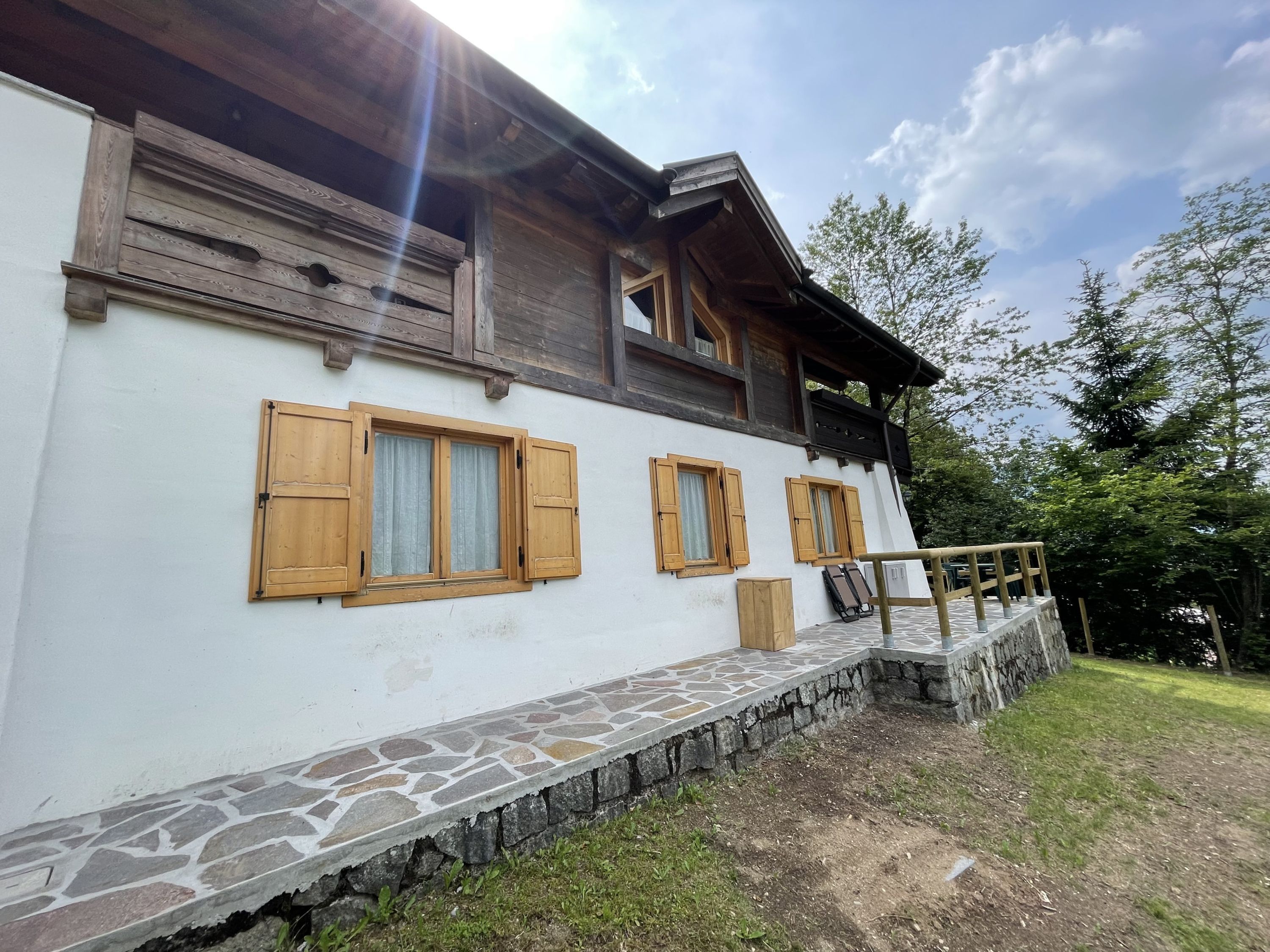 Un bâtiment rustique avec des volets en bois, des marches en pierre et un mur de pierre.