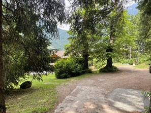 A gravel path leading to a building surrounded by dense trees and a mountain in the background. - 096 Bilocale Immerso nel Verde Pinzolo (Pinzolo)