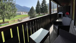 A balcony with wicker furniture, a table, and a view of a mountain landscape. - 082 Bilocale Pinzolo (Pinzolo)