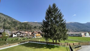 A residential area with houses, a large tree, and mountains in the background. - 082 Bilocale Pinzolo (Pinzolo)