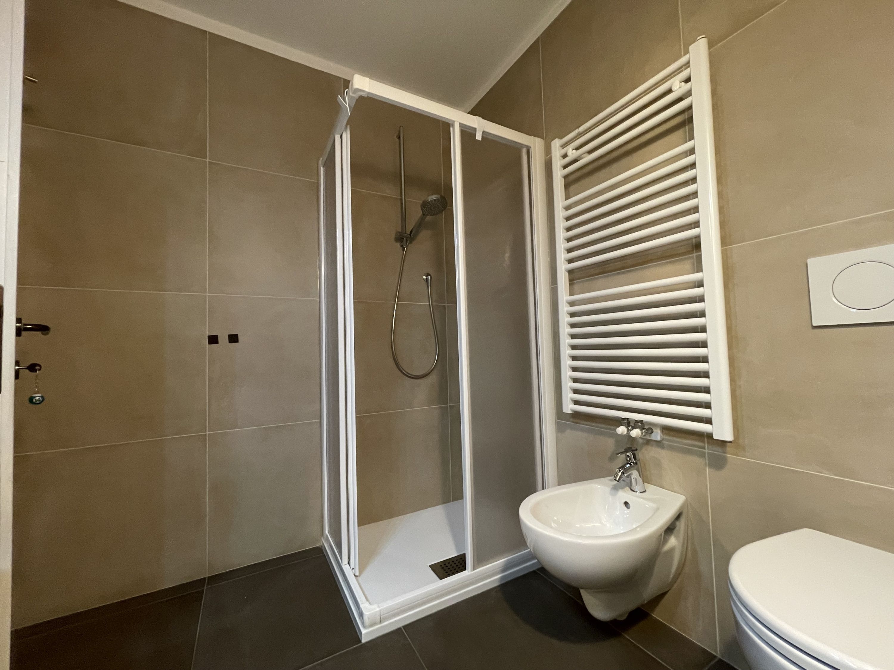 Un baño moderno con ducha de mampara de vidrio, un bidé y un inodoro.