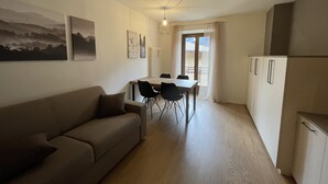 Un espacio habitable compacto con sofá, mesa de comedor, sillas y kitchenette.