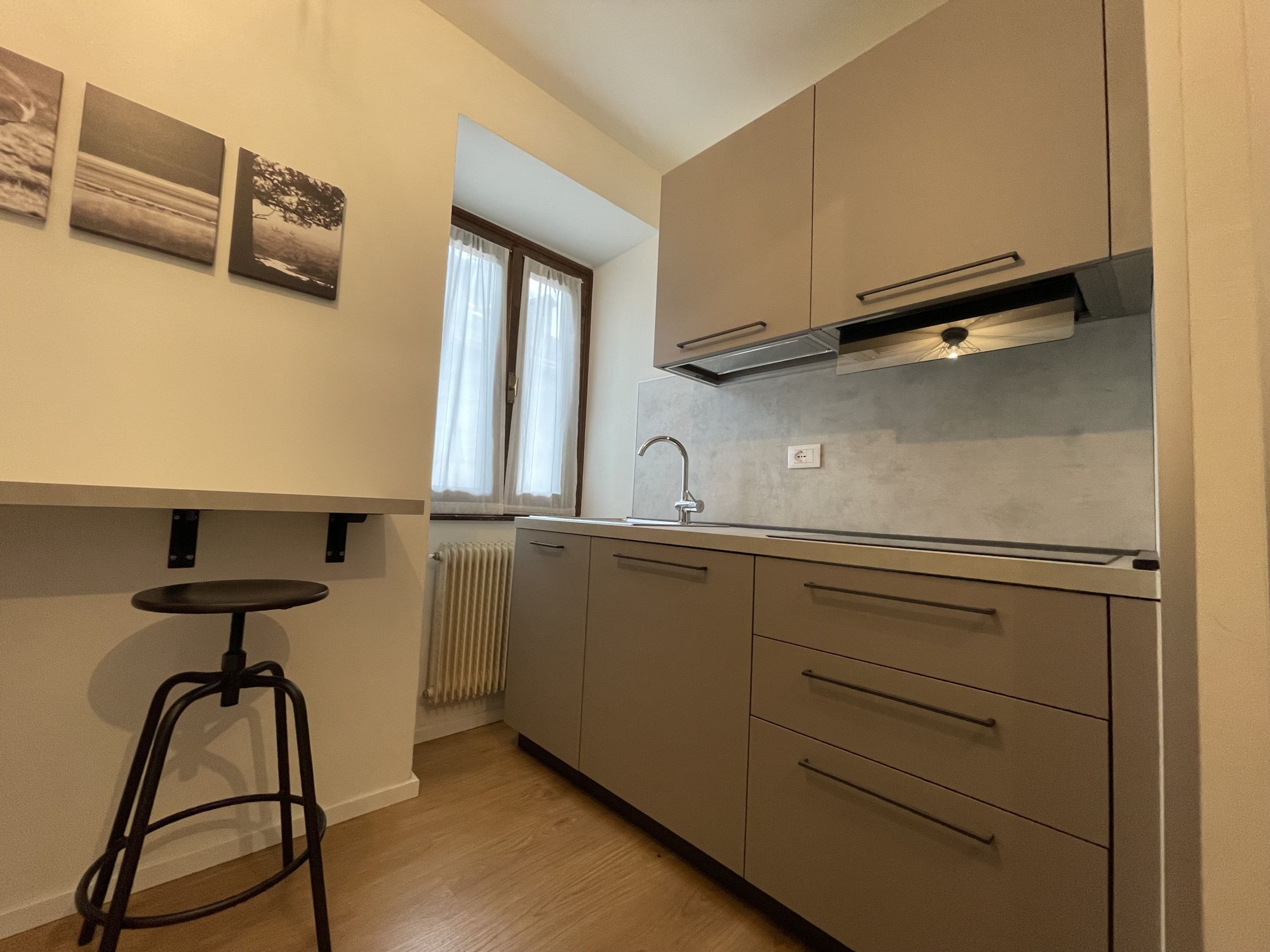 Una cocina moderna con estufa integrada, lavamanos y ventana con cortinas.