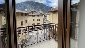 Un balcón con barandilla de metal que da a una ciudad con edificios tradicionales y una montaña al fondo.