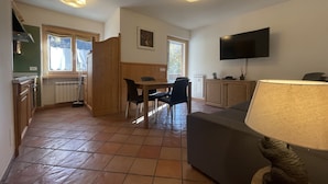 A compact living space with a kitchenette, dining area, and a TV mounted on the wall.
