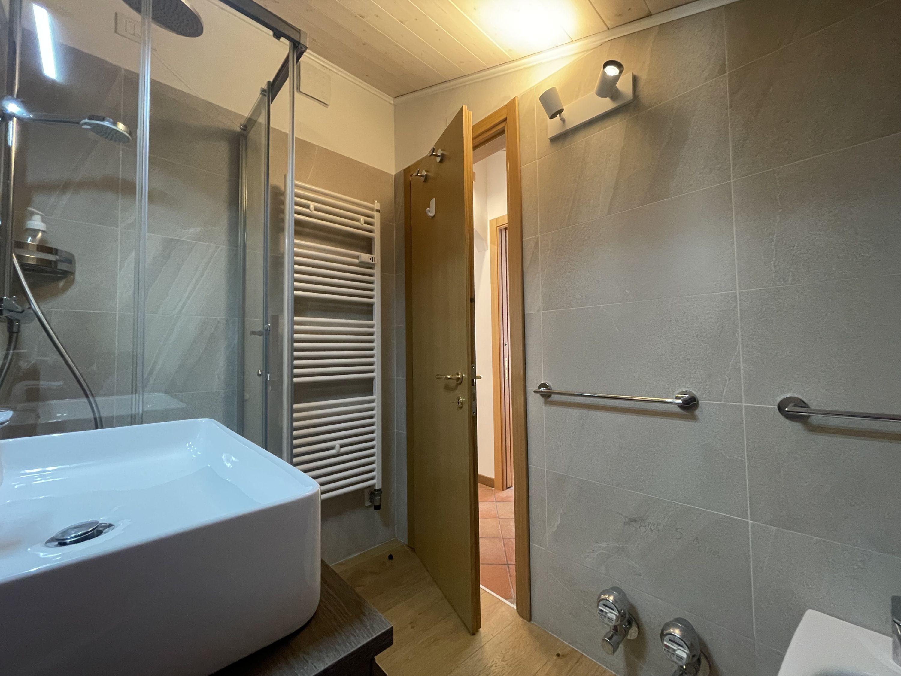 A bathroom with a bathtub, a glass shower enclosure, and a towel rack.