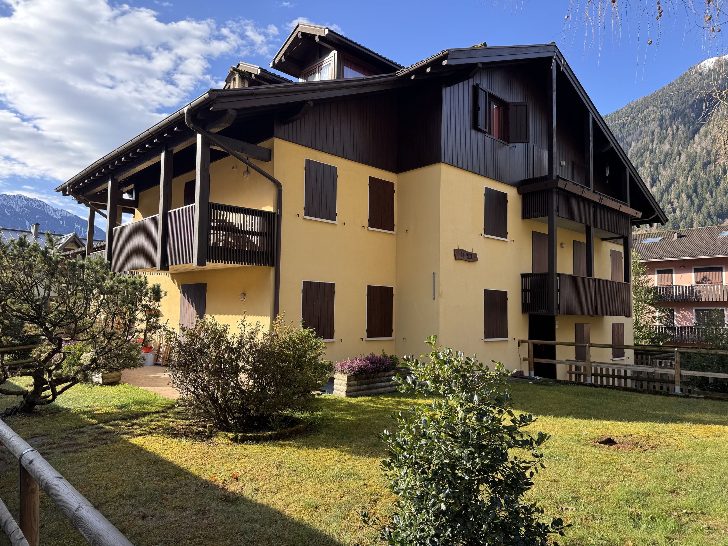 Un immeuble à plusieurs étages doté de balcons, une enseigne indiquant « Lodge », et un paysage montagneux en arrière-plan.