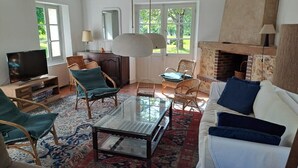 A cozy living room with a fireplace, wicker furniture, and a glass coffee table.
