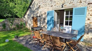 A rustic stone building with a wooden table and chairs outside.