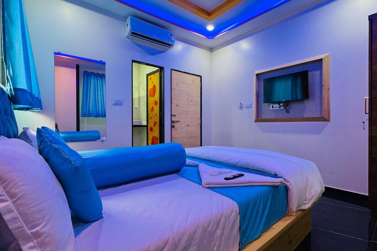 Un dormitorio moderno con una cama grande, un televisor montado en la pared y un equipo de aire acondicionado.