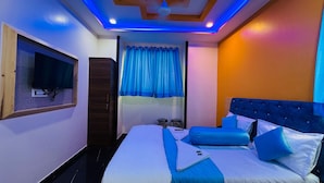 A modern hotel room with a large bed, a flat-screen TV mounted on the wall, and a ceiling fan. - Welcome Star (Mumbai)