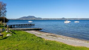 A waterfront with a wooden dock, calm water, and boats.
