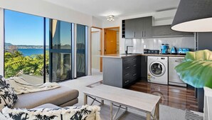 A modern apartment with a balcony, a washing machine, and a kitchen area.