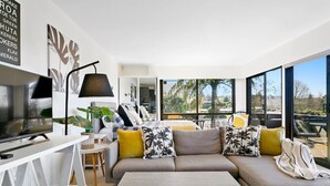 A modern living room with a large sofa, a TV, and a dining area.