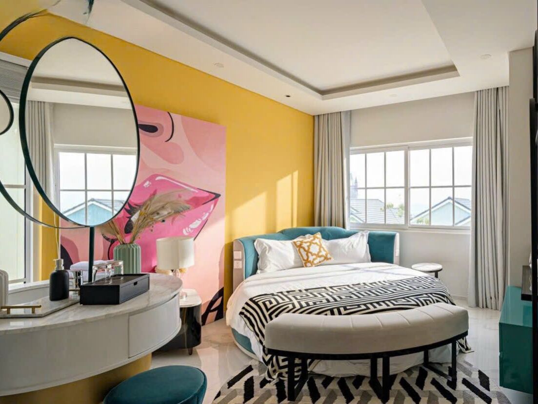 Una habitación de hotel moderna con una cama grande, un escritorio curvo y un espejo amplio.