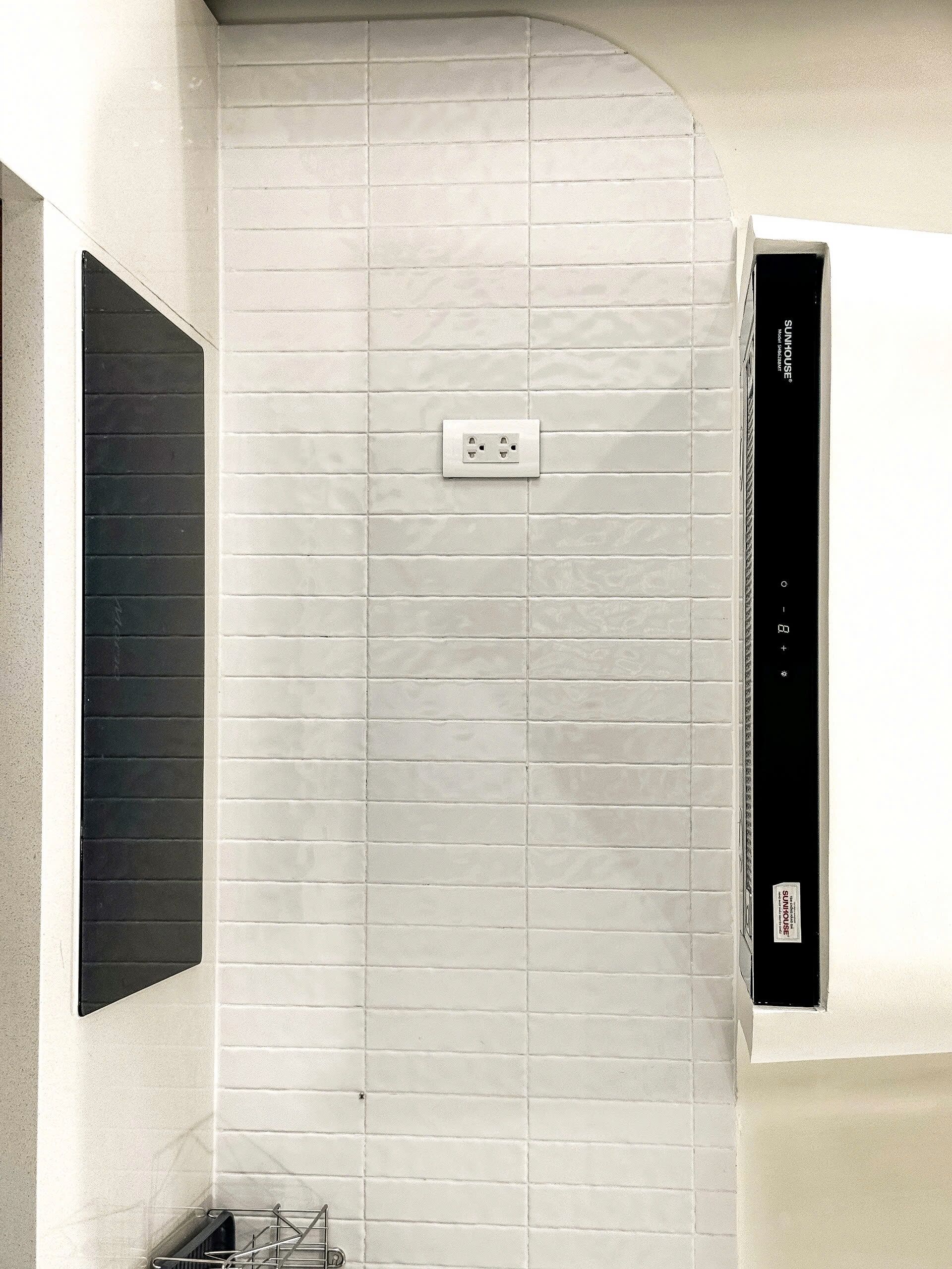 A bathroom with white tiled walls, a black door, and a built-in washing machine.