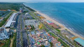 Luchtbeeld van een kustpretpark met een reuzenrad, strand en aangrenzende gebouwen.