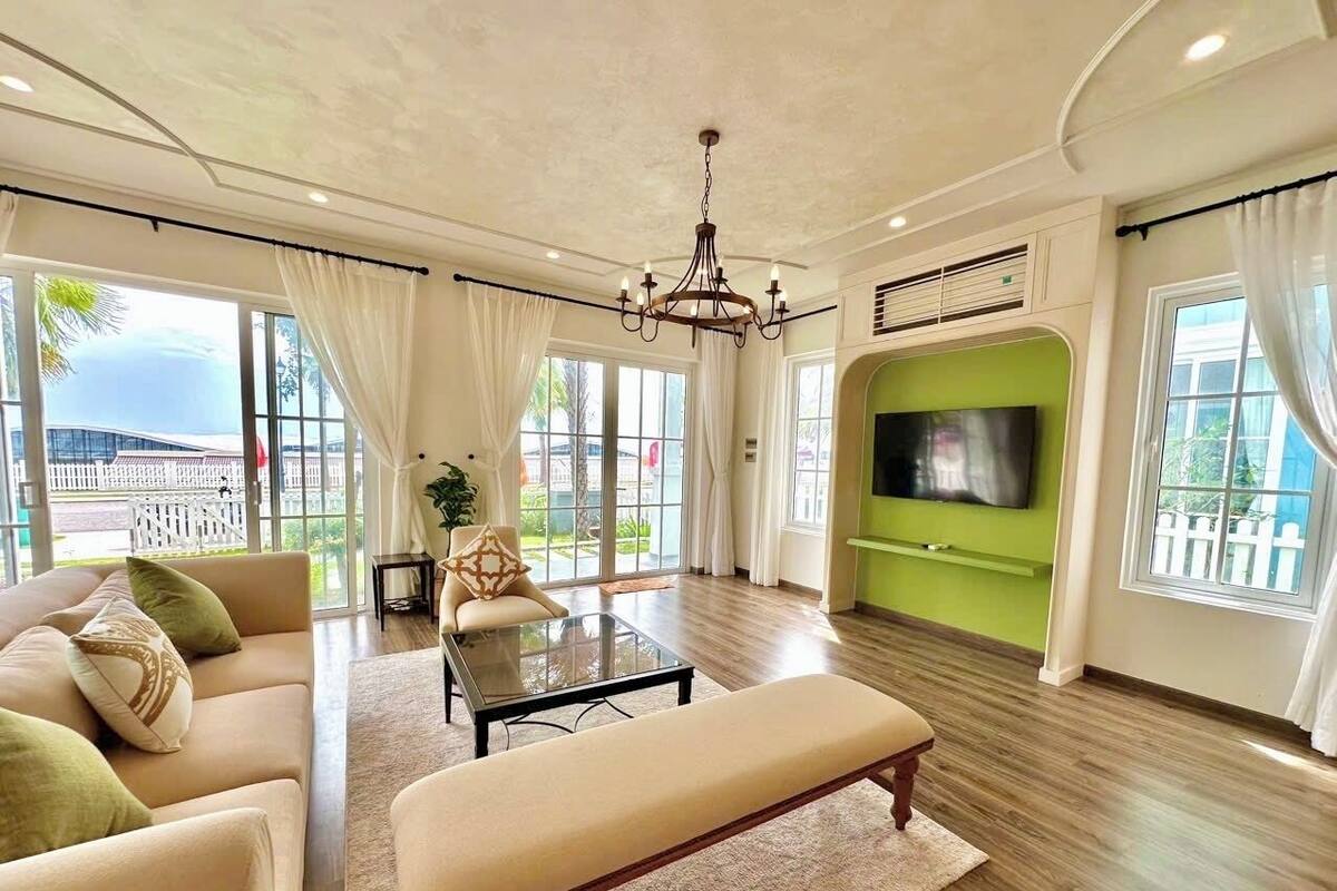 A spacious living room with a large TV, comfortable seating, and a view of the outdoors.