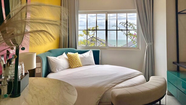 Una camera da letto con un letto, una finestra vista mare e una parete verde.