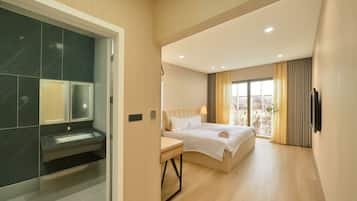 A modern hotel room with a bed, a desk, and a large window offering a city view.