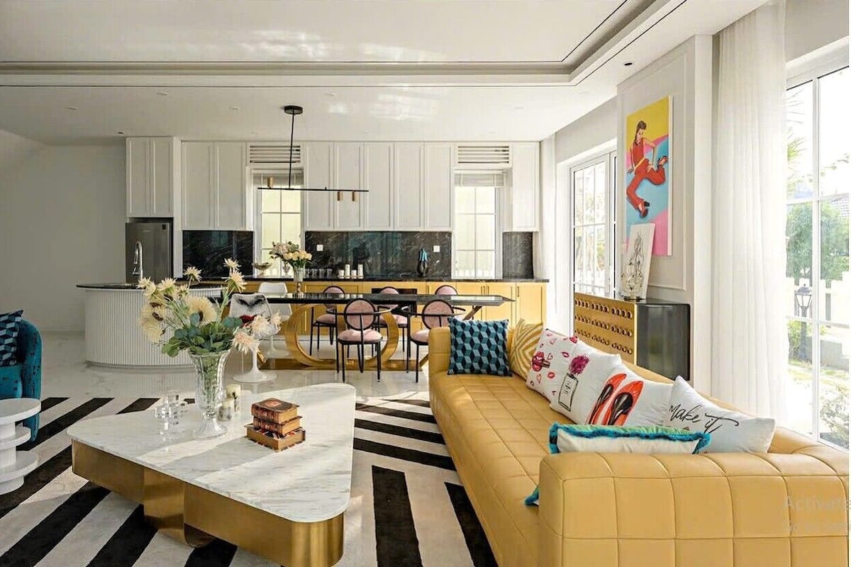 A modern living room with a sofa, coffee table, and a dining area with chairs and a table.