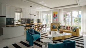 Una cucina moderna con mobili bianchi, un'isola centrale e una zona pranzo con un divano giallo e un tappeto a righe.