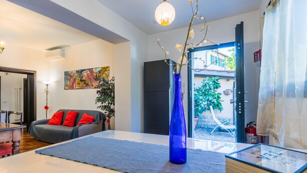 Ein modernes Wohnzimmer mit einer Couch, einer blauen Vase und einem Glastisch.