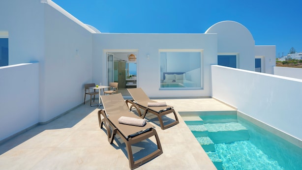 A modern outdoor pool area with lounge chairs and a dining table. - Hilas suites (Imerovigli)