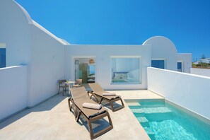 A modern outdoor pool area with lounge chairs and a dining table. - Hilas suites (Imerovigli)