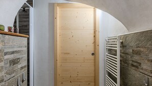 A wooden door in a hallway with a stone wall and a radiator.