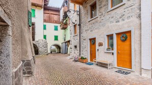A cobblestone street in a historic town with stone buildings, wooden balconies, and a small bench.