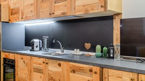 A kitchen with wooden cabinets, a stainless steel sink, a toaster, and a refrigerator.