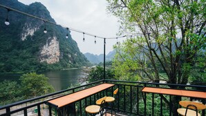 A terrace with tables and chairs overlooking a river and mountains. - Trang An Freedom Hood (Tay Hoa Lu)