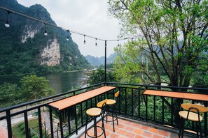 A terrace with tables and chairs overlooking a river and mountains. - Trang An Freedom Hood (Tay Hoa Lu)
