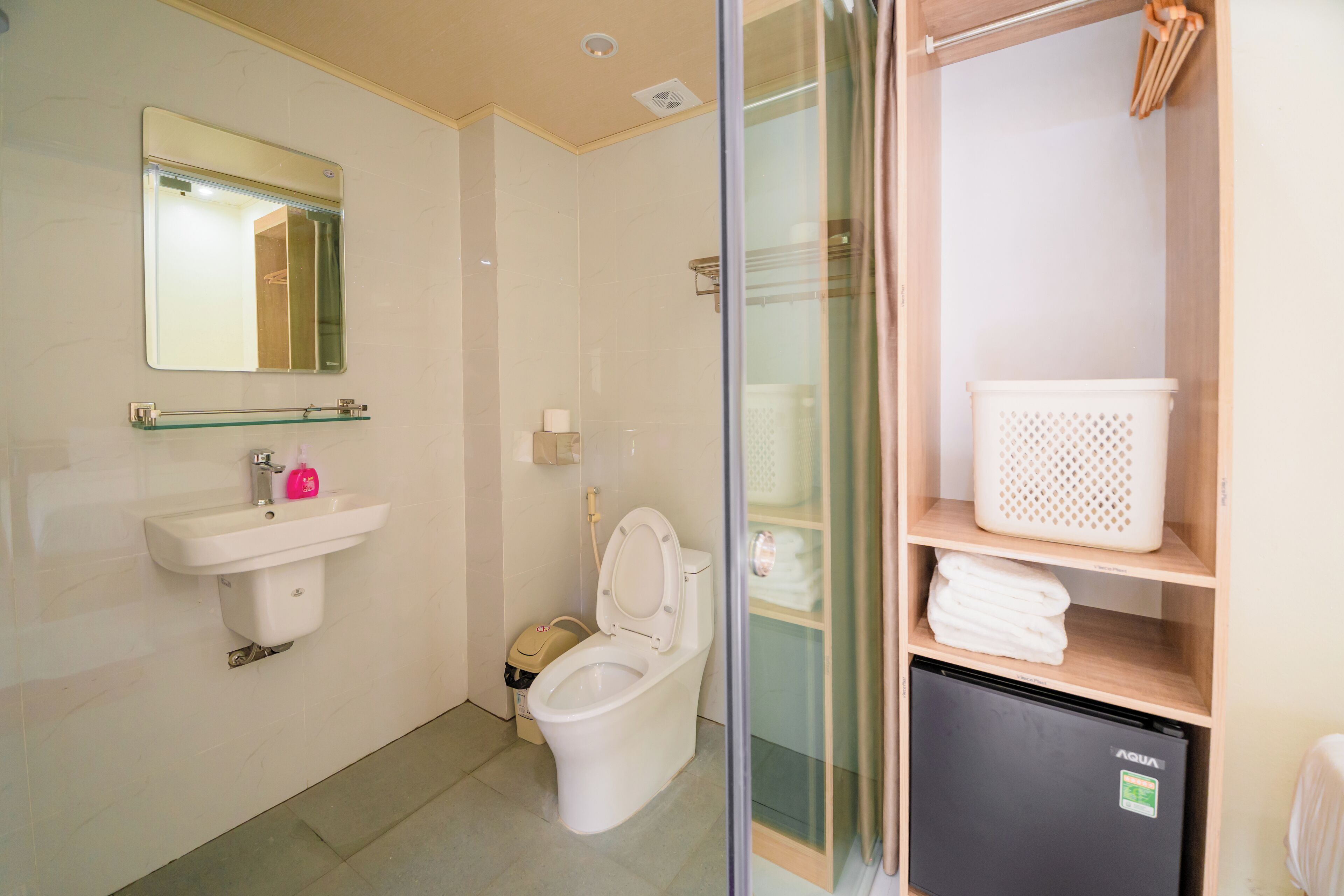 Un baño con lavamanos, inodoro y un refrigerador pequeño.